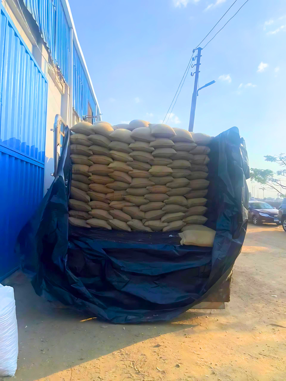 Crops Truck bed loaded with stacked sacks, covered with a black tarp. Exporter